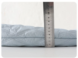 Detail showing 4-5cm thickness of blue quilted baby winter romper with ruler measurement