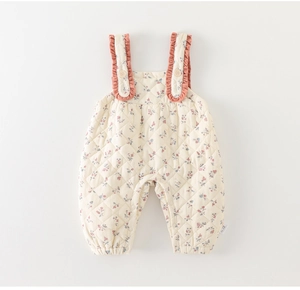 Detailed macro view of floral quilted baby romper with ruffled straps and soft cotton texture