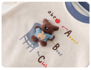 Dettaglio tutina neonato con toppa orso 3D e stampa educativa colorata con alfabeto ABC
