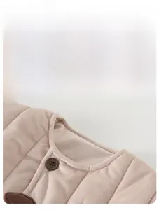 Close-up of baby quilted cotton jacket with soft texture, round neck and brown button