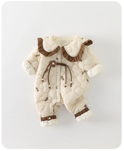 Détail d'une barboteuse matelassée pour bébé avec col à volants marron et fleurs en 3D