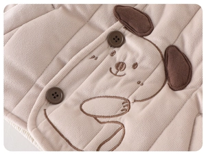 Detailed close-up of beige quilted baby jacket featuring cute puppy embroidery and brown buttons