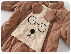 Detail of baby quilted romper showing brown fabric and cute cartoon bear embroidery