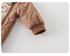 Close-up of brown quilted baby romper with cartoon eye patch and elastic ribbed cuffs