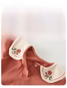 Detailed close-up of cherry blossom embroidery on a white collar of a baby floral romper