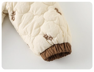 Détail de la barboteuse matelassée pour bébé avec broderies fleurs et poignets élastiques