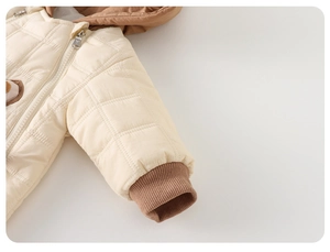 Detail view of square-quilted infant romper with ribbed cuffs and warm cream fabric