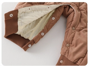 Detail of baby quilted jumpsuit showing ribbed cuffs and snap button closure