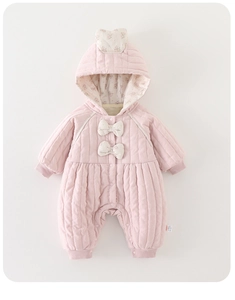 Detail of pink quilted baby romper with floral lining and bows on white background