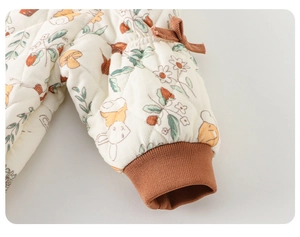 Detalle de pelele acolchado para bebé con puño elástico marrón y lazo decorativo suave