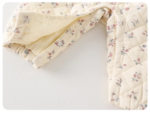 Detail of floral quilted baby romper featuring diamond stitching and white snap buttons
