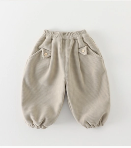 Détail du pantalon gaufré pour bébé en beige avec taille élastique et bouton en bois