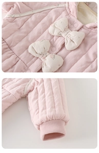 Detail of pink quilted baby romper featuring a floral bow and elastic ribbed cuffs
