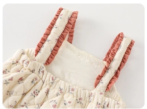 Macro detail of quilted floral baby romper featuring rose ruffles and soft texture
