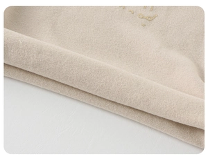 Gros plan sur maille beige douce avec broderie dorée élégante et texture côtelée