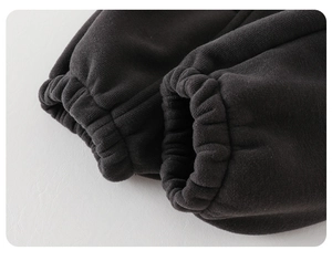 Détail macro des poignets élastiques sur un pantalon en molleton noir épais pour enfants
