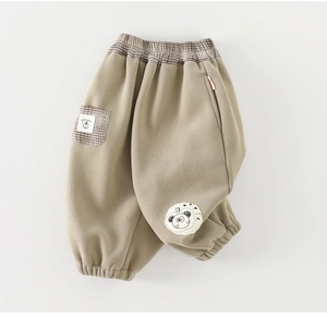 Detail view of khaki girls' trousers featuring brown plaid pockets and a cute cartoon patch