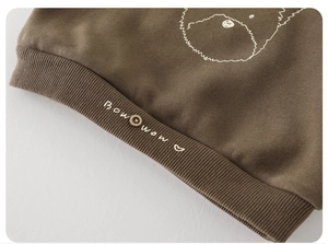 Detailed close-up of dark brown toddler sweatshirt featuring puppy embroidery and rib hem