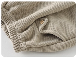 Détail du pantalon gaufré pour bébé avec taille élastique et poche à bouton en bois