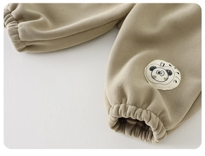 Detail of girls beige fleece jogger pants featuring a cute panda patch and elastic cuffs