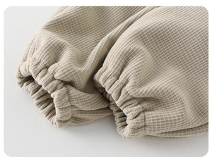 Détail rapproché du tissu gaufré beige chaud avec bords-côtes sur ce pantalon bébé d'hiver