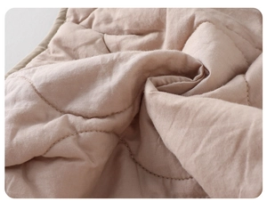 Close-up of quilted fabric texture with curved stitching on warm beige winter set