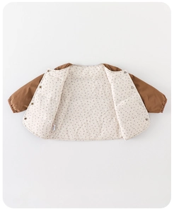 Detail of children quilted jacket with brown sleeves, floral lining and snap buttons