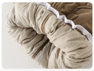 Detail of baby pants with brown corduroy fabric, warm padding and wavy trim edges