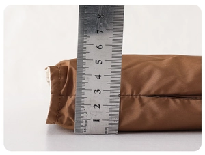Detail showing the 5.5cm thickness of a warm brown down jacket lining using a steel ruler