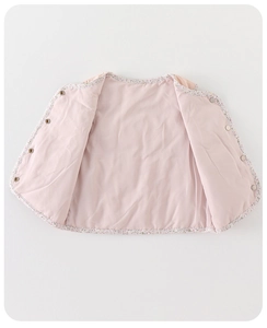 Gros plan détaillé d'un gilet en duvet pour bébé rose avec passepoil floral et boutons