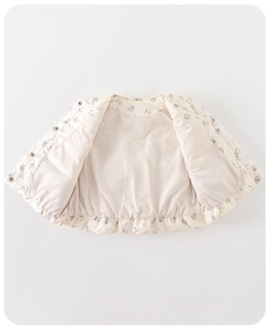 Détail du gilet à fleurs pour bébé avec boutons-pression et ourlet à volants