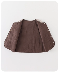 Detailed view of kids quilted brown vest featuring floral inner lining and snap buttons