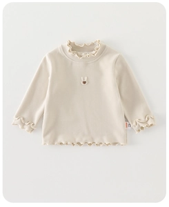 Détail du sous-pull bébé beige avec broderie lapin et finitions délicates à volants