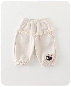 Détail du pantalon crème pour bébé fille avec taille en dentelle et patch panier