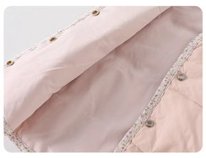 Détail de la doublure de gilet rose avec bordure fleurie et boutons-pression