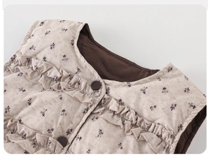 Detailed close-up of children's floral down vest featuring ruffle trim and brown buttons