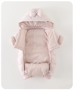 Detail of pink baby winter romper with large bow hood and white polka dot texture