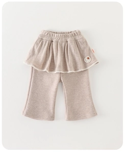 Detail of baby girl's knitted flared trousers with layered ruffle skirt and heart patch