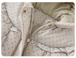 Détail de veste matelassée fleurie pour bébé avec volants et fermeture éclair en métal