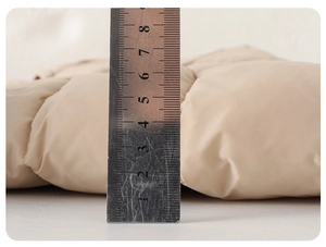 Macro view of the padded winter jacket showing 4cm thickness with a metal ruler measurement
