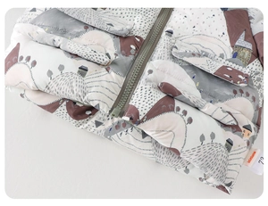 Close-up of quilted winter jacket fabric with Nordic house prints and smooth zipper detail