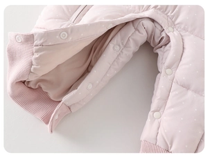 Detailed macro view of pink quilted baby romper featuring white polka dots and snap buttons