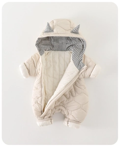 Détail d'une combinaison bébé hiver avec matelassage hexagonal et capuche à oreilles