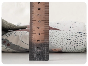 Detail showing the thickness of the cartoon printed infant winter jacket padding with ruler