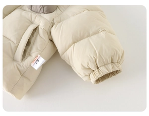 Détail des poignets élastiques et coutures de poche sur veste d'hiver beige pour bébé