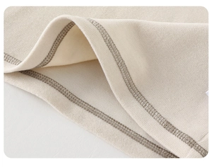 Vue macro détaillée des coutures renforcées sur le manteau doux en coton beige pour bébé