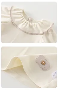 Close-up of baby cotton top with floral Peter Pan collar and decorative wooden button