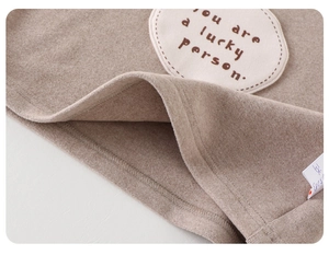 Close-up of brown fleece baby jacket showing warm texture and lucky person embroidery
