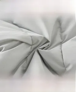 Detailed macro shot of light grey quilted fabric with diamond stitch for baby winter romper