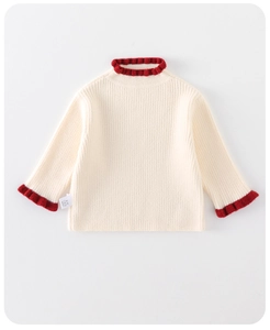 Detail eines weichen Strickpullovers in Creme mit rotem Rüschenkragen und Rippmuster